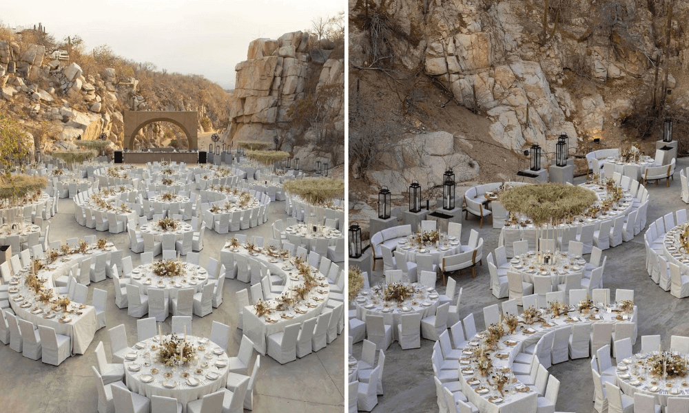 Elegant outdoor dining setup with circular white-clothed tables and white floral centerpieces, set against a dramatic backdrop of rocky mountain terrain